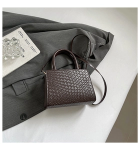 Macro view of dark brown faux leather woven texture and handle detail on a small square bag