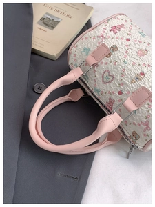 Close-up of a sweet barrel handbag featuring cartoon bear patterns and pink leather handles