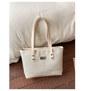 Dettaglio della borsa tote in tessuto intrecciato con manici in pelle e rivetti in metallo