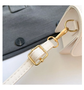 Detailed view of the white leather handbag strap with gold buckle and fine stitching