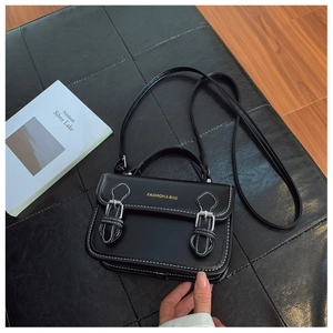 Detail view of black PU leather crossbody bag with white stitching and silver buckles