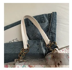Detail of floral tote bag featuring gold chain handle and a white plush bear charm