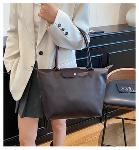 Detail of a dark brown faux leather tote bag with flap closure and slim shoulder straps
