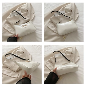 Dettaglio della borsa a spalla in pelle verniciata bianca con fiocco in metallo dorato