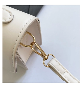 Close-up of dual stitching and gold metal swivel hook on cream leather handbag detail