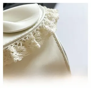 Close-up of elegant cream bow and delicate white lace embroidery on a soft faux leather bag