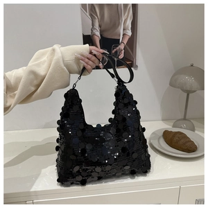 Detail of a chic black sequined hobo bag being held, showcasing glossy round sequins