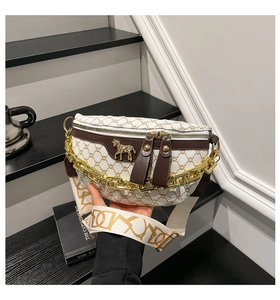 Detail of wide jacquard strap and gold chain on patterned white crossbody chest bag