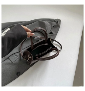 Top view of the interior compartment and gold zipper detail of this brown woven handbag