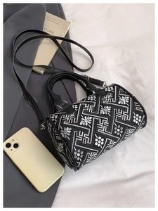 Close-up of black embroidered bucket bag with floral patterns on a white cloth