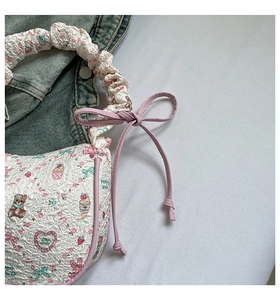 Detail of white quilted handbag with pink strawberry and cartoon bear prints
