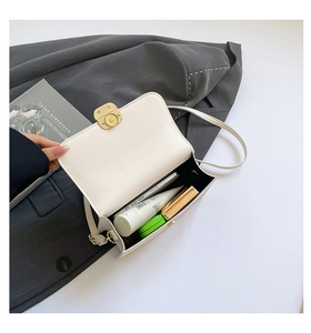 Internal view of a white leather square bag showing phone and cosmetics storage