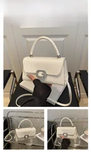 Detail view of white glossy leather handbag with silver G buckle and crossbody strap