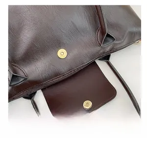 Detail of metal magnetic snap closure on textured dark brown faux leather tote bag