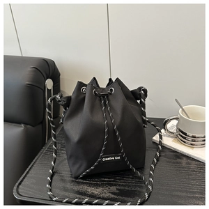 Detailed view of black nylon bucket bag with Creative Cat label and woven drawstring