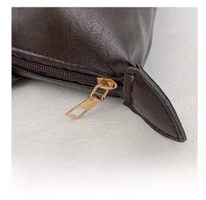 Detailed macro view of high-quality smooth gold zipper on dark brown leather bag texture