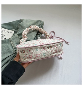 Detail of white pleated handbag with pink floral bear print and leather trim