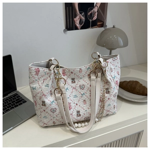 Detail of white textured tote bag with bear print, pearl charms and gold chain handles