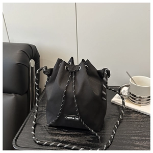 Detail of nylon bucket bag featuring a black and white woven drawstring and silver grommets