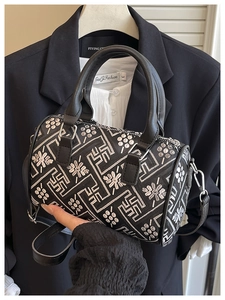 Detailed close-up of a black Boston bag with white floral embroidery and dual handles
