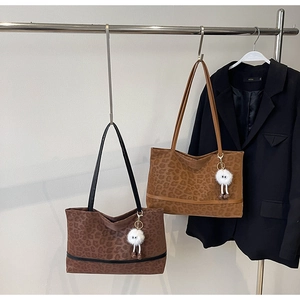 Detail of large leopard print tote bags in brown and khaki with creative plush charms