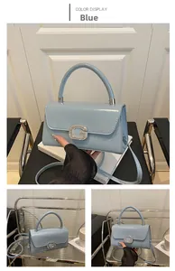 Detail of blue glossy PU leather bag featuring a sparkling rhinestone G buckle