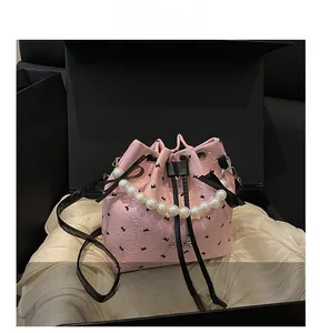 Vue détaillée du sac seau rose avec imprimés papillons et poignée en perles
