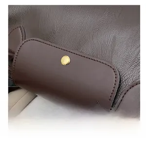 Detail of dark brown leather texture with golden metal snap button and fine stitching