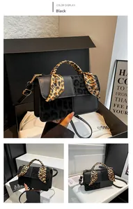 Detail of black crossbody bag with leopard print panel and silk scarf on handle