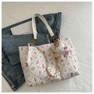 Detail view of floral bear tote with pearl chain and blue hoodie bear plush charm