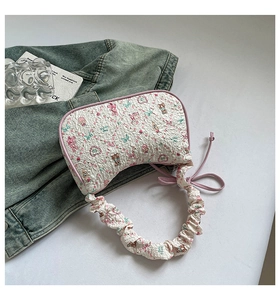 Detail of white seersucker underarm bag with pink bunny prints and purple ruffled strap