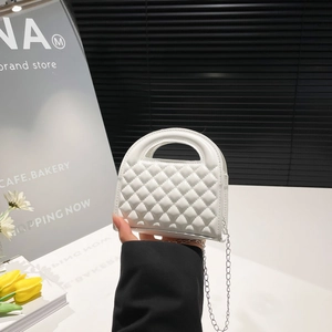 White quilted mini handbag with silver chain strap and top handle in a stylish lifestyle setting