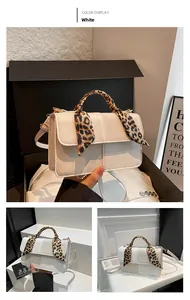 Detail view of a white textured crossbody bag featuring a leopard print scarf handle