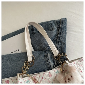 Detail of white floral tote bag featuring a gold chain strap and plush bear pendant