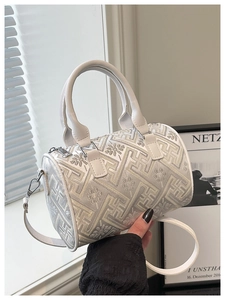 Detail of white bucket bag featuring intricate floral embroidery and leather handles