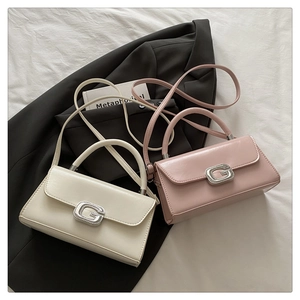 Close-up of small crossbody bags with G-buckle hardware and glossy leather texture