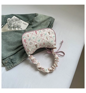Close-up of white embossed fabric underarm bag featuring pink floral and bear prints