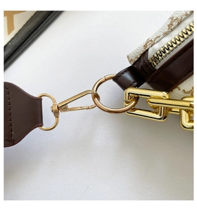Detailed macro view of gold metal buckles and brown leather straps on a monogram crossbody bag