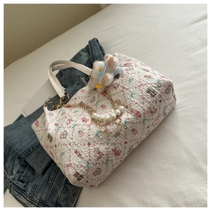 Detail of white textured tote bag with cute pink bear print and pearl chain accessory