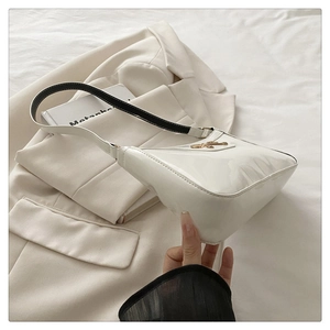 Dettaglio borsa a spalla in pelle verniciata bianca con fibbia dorata su blazer bianco