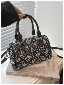 Detailed view of black bucket bag with silver floral embroidery and leather handles