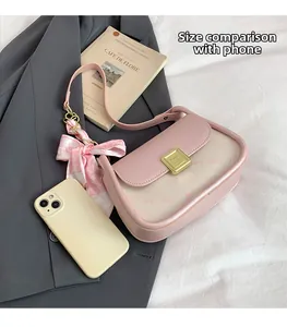 Detail of pink and beige crossbody bag with gold buckle and decorative floral silk scarf