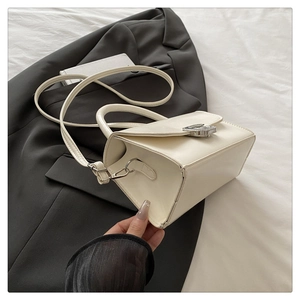 Close-up of cream PU leather handbag featuring a silver buckle on a black blazer