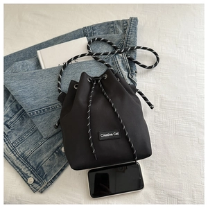 Top view of a black drawstring bucket bag showing its capacity next to a smartphone