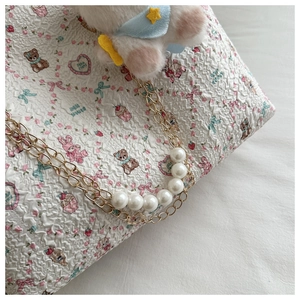 Detail of quilted tote with cartoon prints and elegant pearl gold chain strap