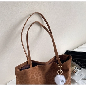 Close-up of leopard print tote bag with brown faux suede texture and furry eye charm