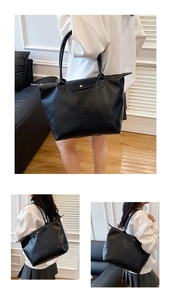 Detail view of large black tote bag with top zipper closure and adjustable shoulder strap
