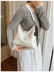 Gros plan d'un sac à bandoulière en cuir verni blanc avec un charmant foulard sur le côté