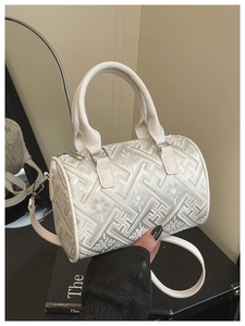 Close-up of white bucket bag featuring elegant floral embroidery and metal zipper detail