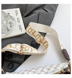 Detailed close-up of patterned wide shoulder strap and beige crossbody bag texture